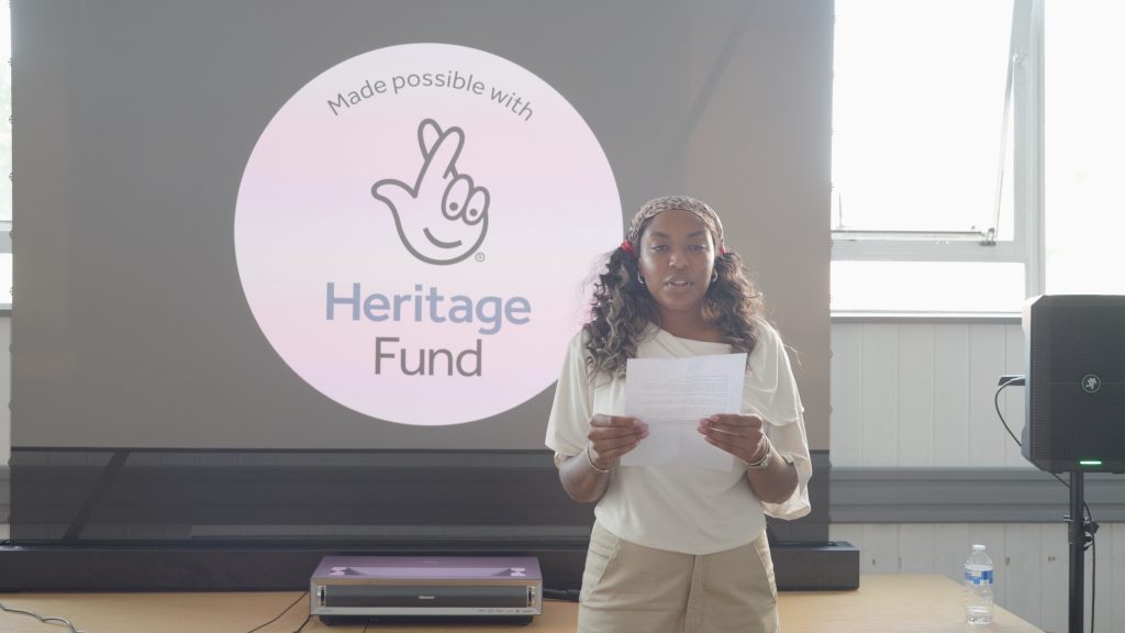 A speaker at the launch, in front of the National Lottery Heritage Fund logo